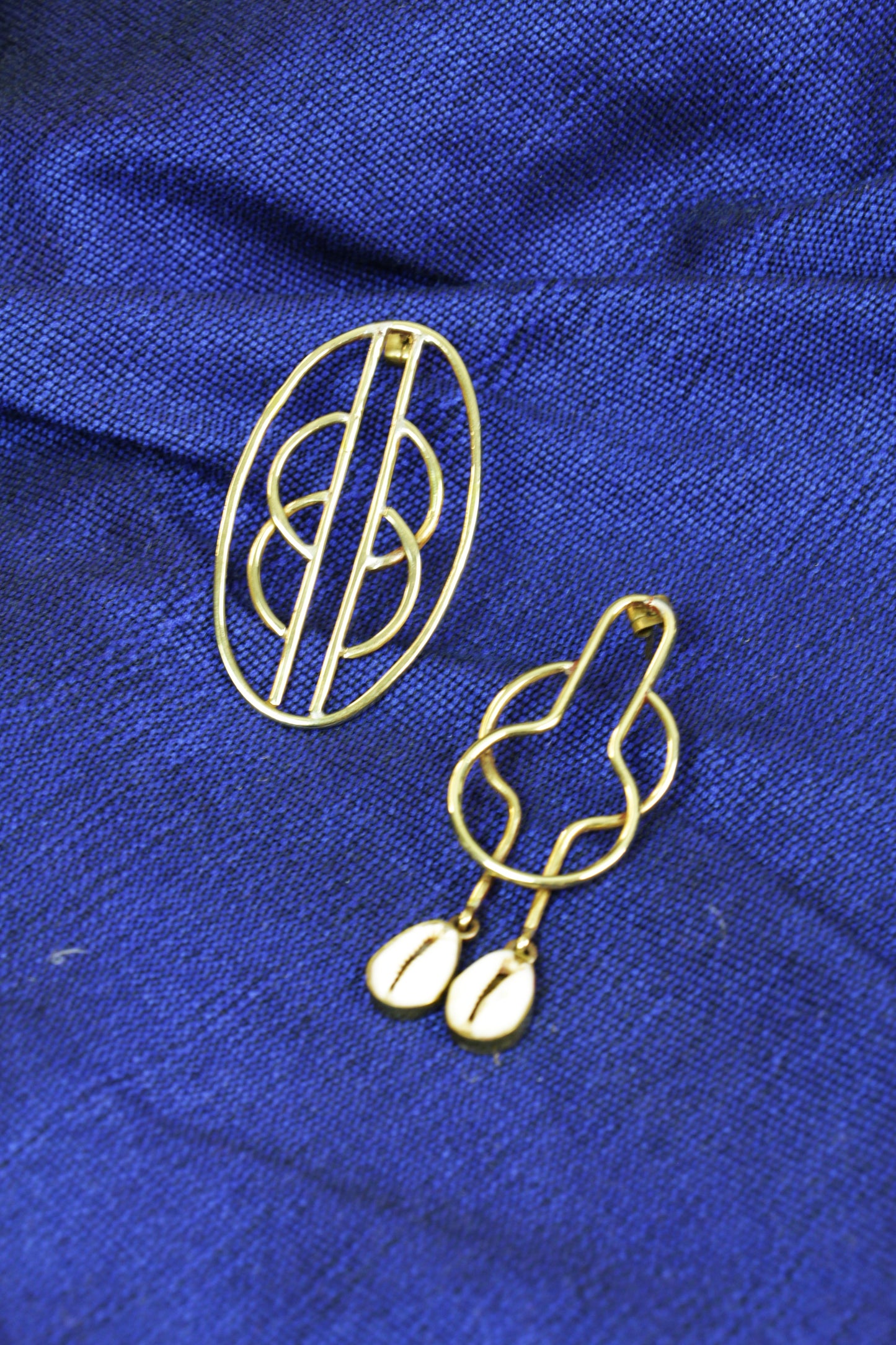 Boucles d'oreilles Kyassa sur un tissu bleu.
