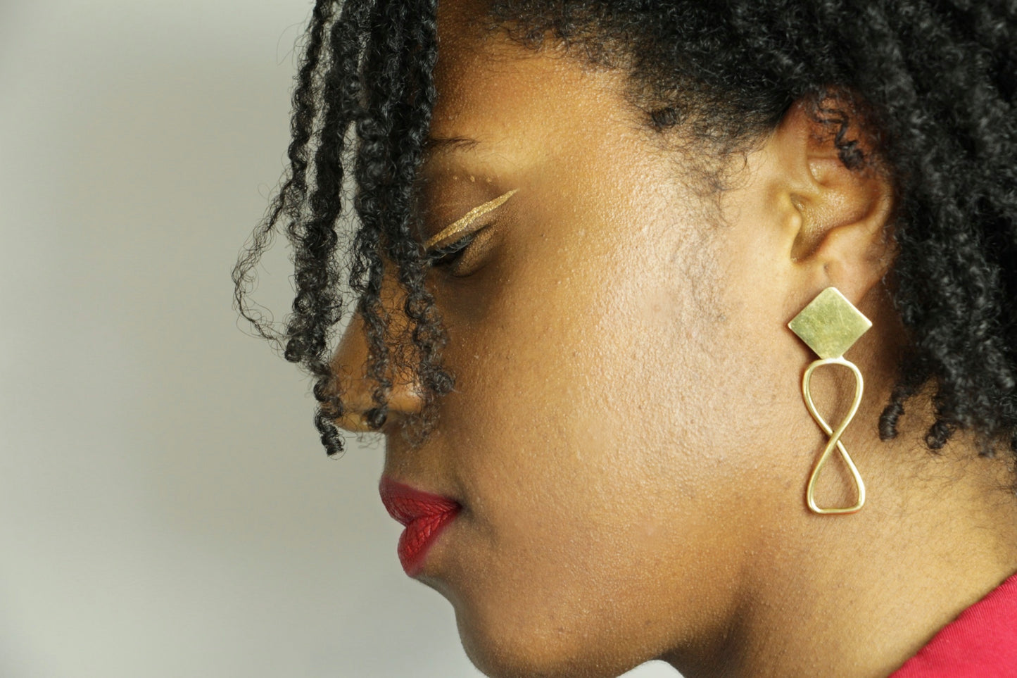 Boucles d'oreilles Adna portée par une femme au maquillage afro ethnique.